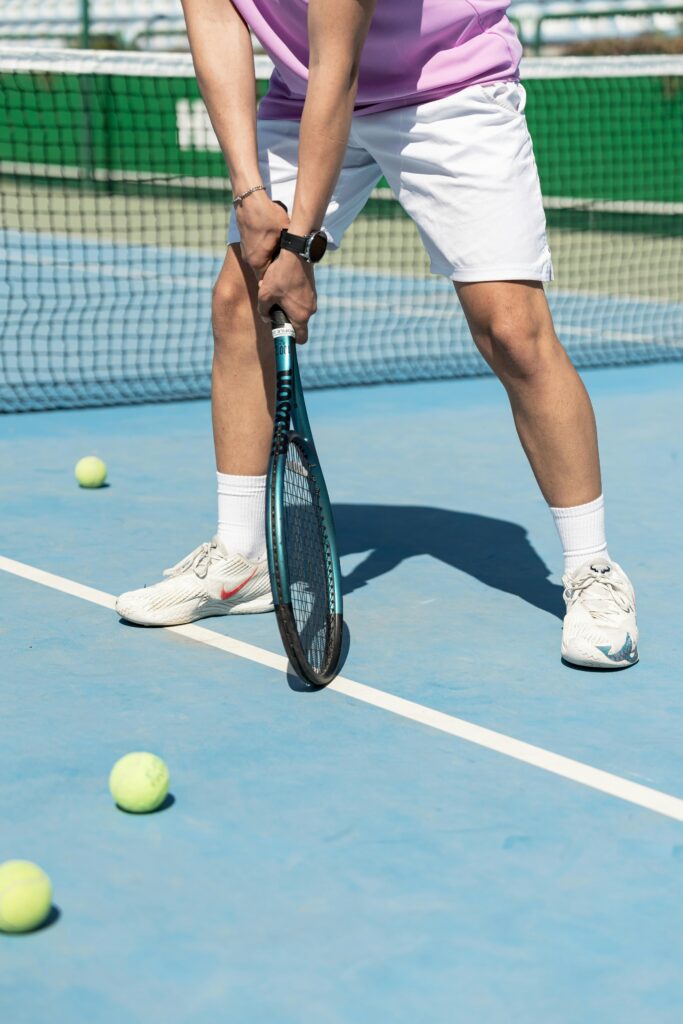 Man in sportswear holding a racket, ready to play on a sunny tennis court.